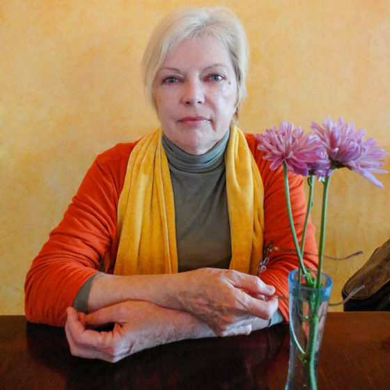 Colorful portrait of grey haired woman at table with flowers