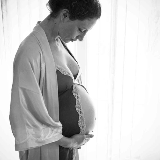 Black and white photograph of pregnant woman in robe and nightie