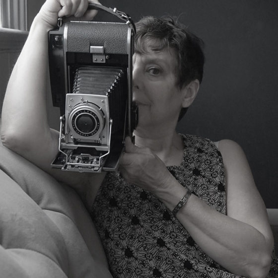Black and white portrait photograph of woman holding vintage camera