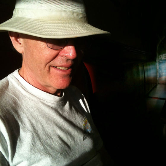 Portrait photograph of man in sunshine wearing cloth hat